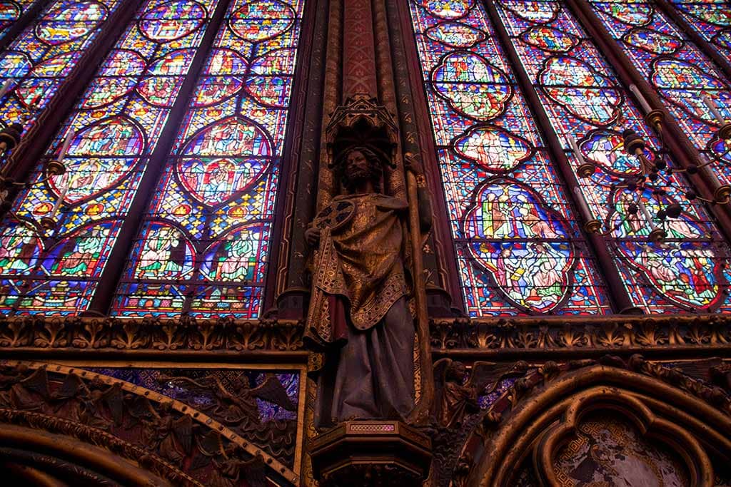Image of a statue of an apostle and stained glass windows in La Sainte Chapelle Paris